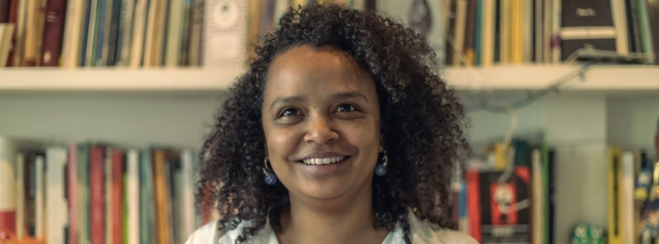 Retrato de Yanelis Núñez Leyva, activista cubana y miembro del Movimiento San Isidro, frente a un estante de libros. Su historia destaca la lucha por la libertad y la esperanza desde el exilio.