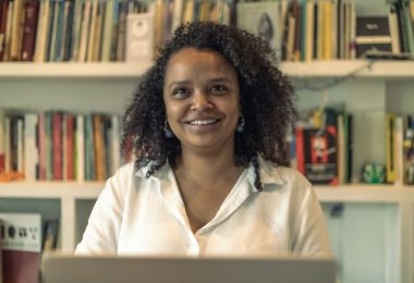 Retrato de Yanelis Núñez Leyva, activista cubana y miembro del Movimiento San Isidro, frente a un estante de libros. Su historia destaca la lucha por la libertad y la esperanza desde el exilio.