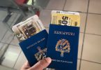 Mano sosteniendo dos pasaportes cubanos y boletos de viaje, simbolizando los procesos de migración desde Cuba hacia Canadá.