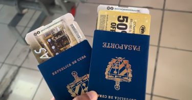 Mano sosteniendo dos pasaportes cubanos y boletos de viaje, simbolizando los procesos de migración desde Cuba hacia Canadá.