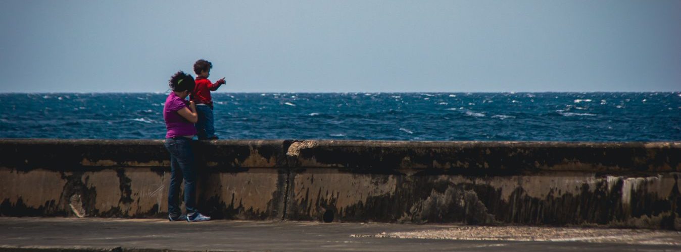 Madre con su hijo observando el mar desde el Malecón de La Habana.