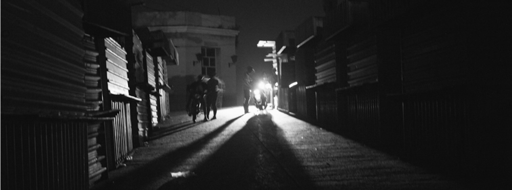 Calle oscura en Cuba, iluminada únicamente por la luz de una motocicleta en medio de un apagón.