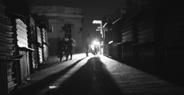 Calle oscura en Cuba, iluminada únicamente por la luz de una motocicleta en medio de un apagón.