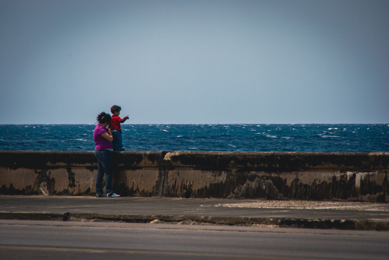 Madre con su hijo observando el mar desde el Malecón de La Habana.