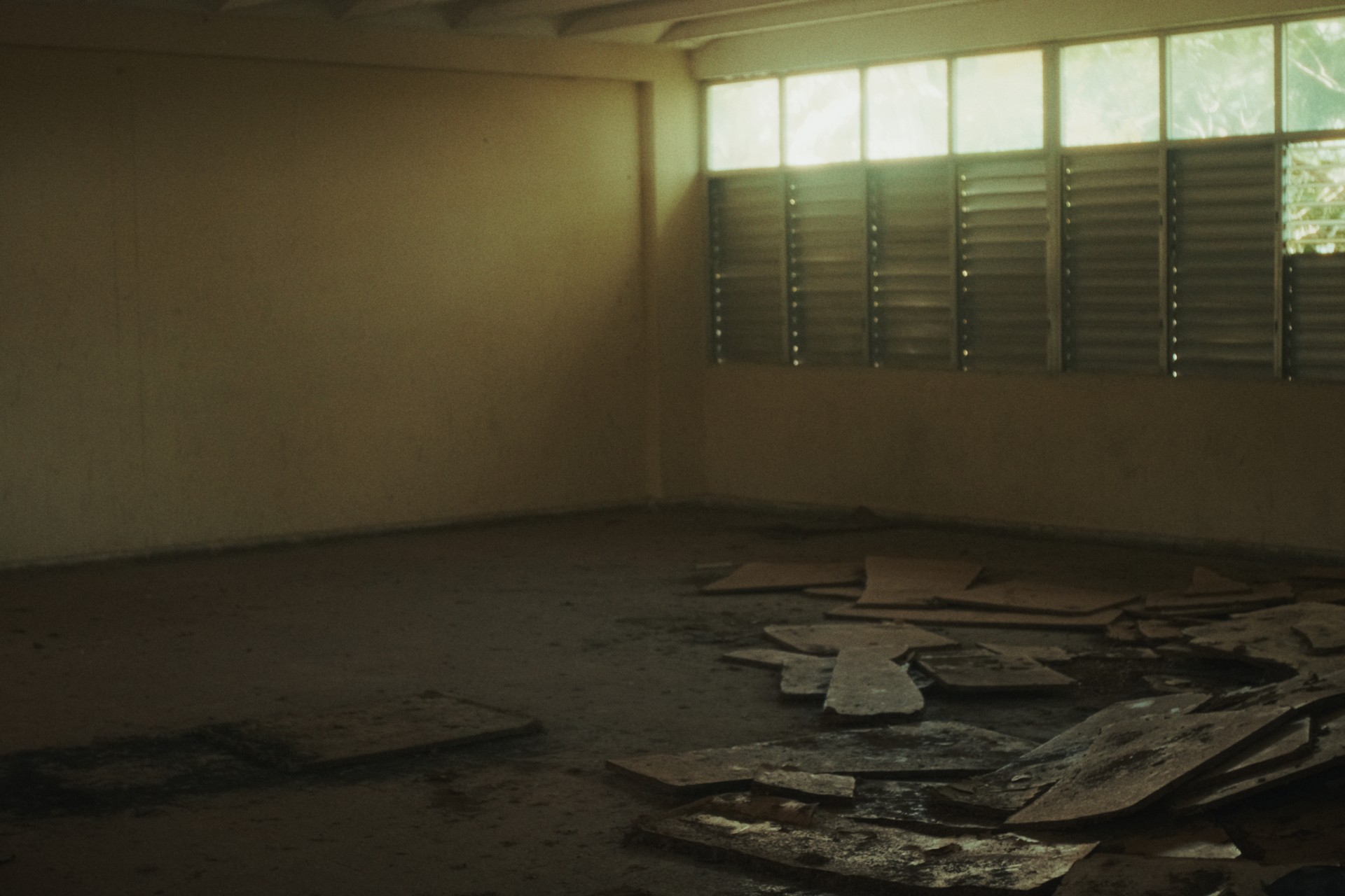 Aula vacía de Ceiba 1 con restos de paneles en el suelo y ventanas de persiana.