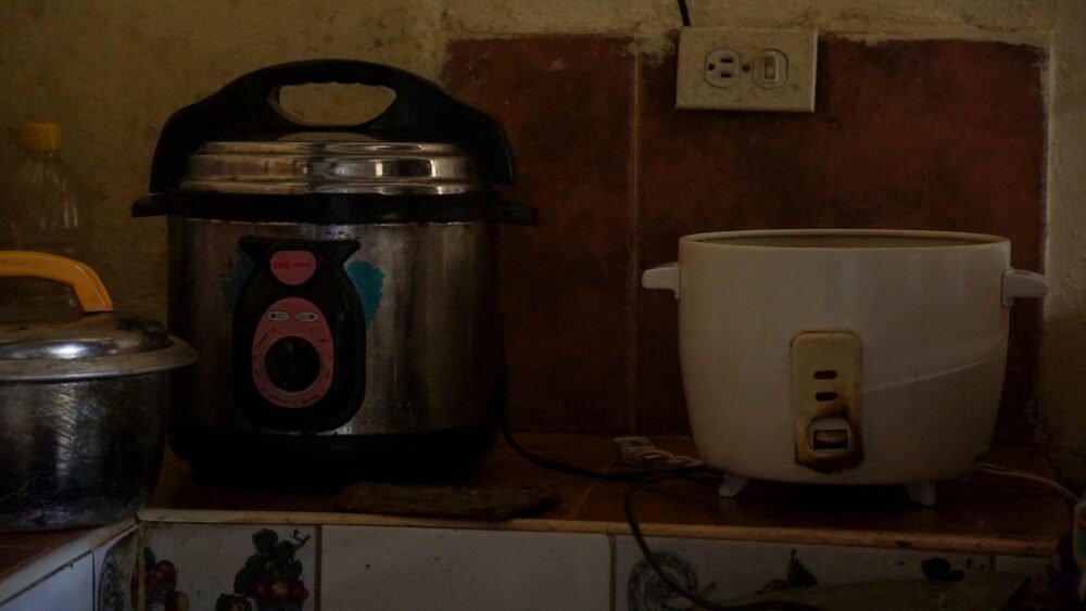 Olla arrocera quemada en una cocina cubana. Problemas de electricidad y comida.