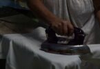 Manos planchando con plancha antigua, rutina de madre soltera.