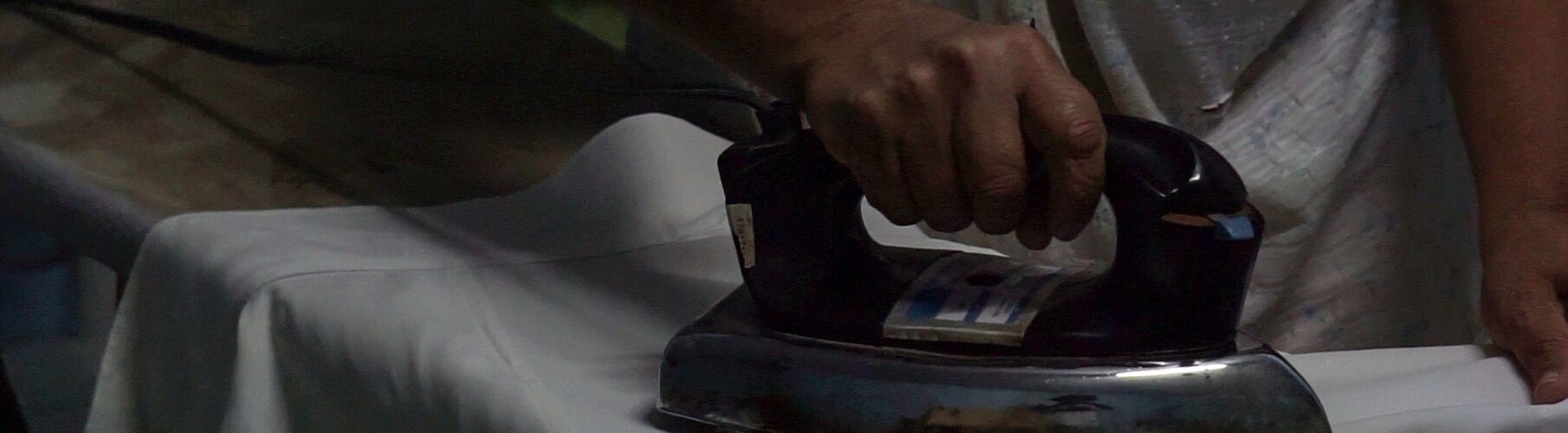 Manos planchando con plancha antigua, rutina de madre soltera.