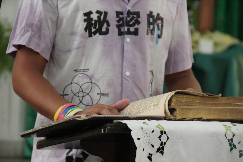 Grupo de hombres rodean a una persona en el centro, colocando sus manos sobre su espalda y hombro en gesto de apoyo y consuelo durante un acto religioso