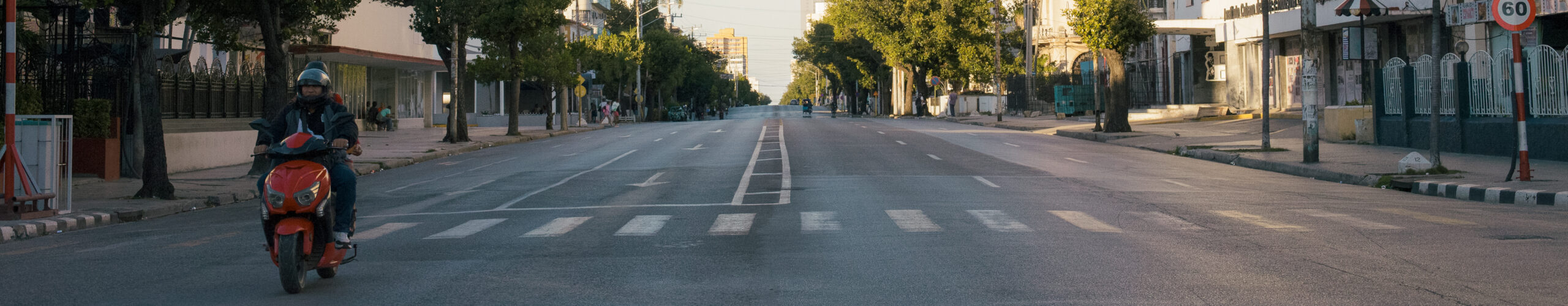 Avenida 23 vacía en horario pico atravesada por una pareja que viaja en moto eléctrica