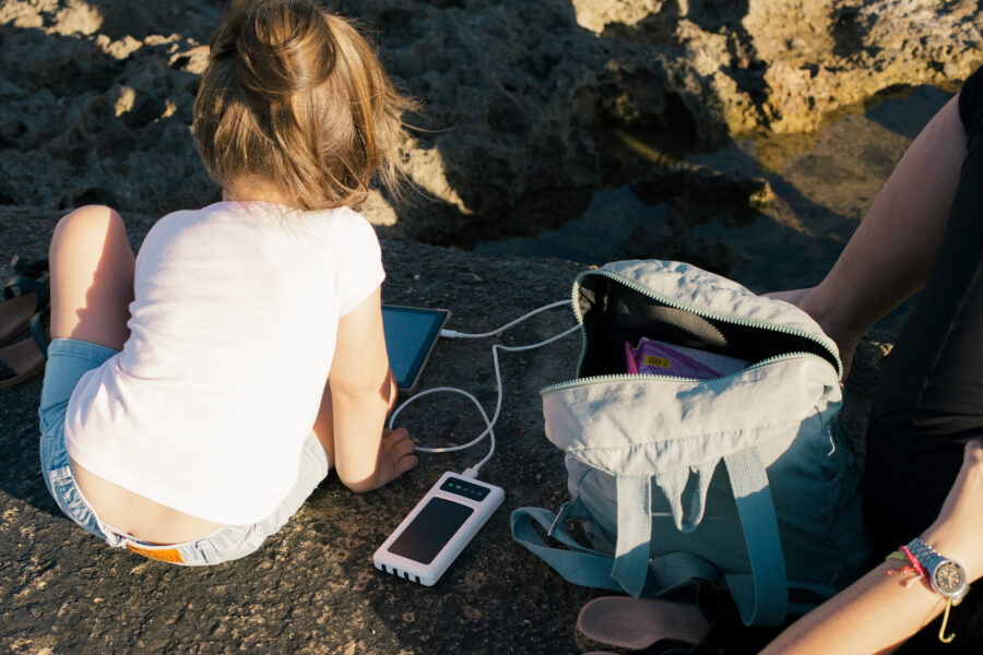 Niña juega con un dispositivo digital en la costa del municipio Playa mientras lo alimenta con una batería de carga solar durante el apagón nacional del 21 de marzo de 2026. 