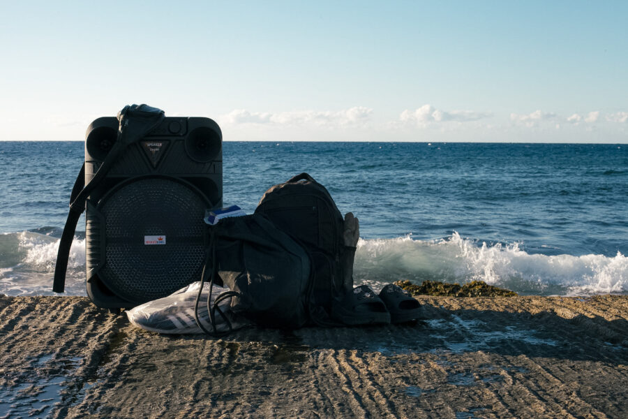 Bocina portátil y pertenencias de jóvenes que se bañan en la costa mientras escuchan música. 