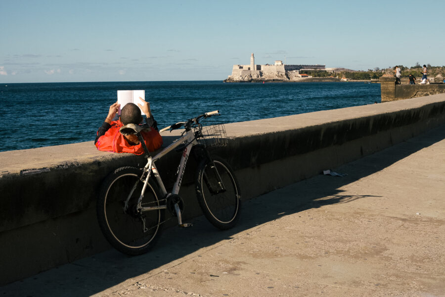Joven leyendo en el malecón de La Habana al lado de su bicicleta durante el apagón nacional del 21 de marzo de 2026. 