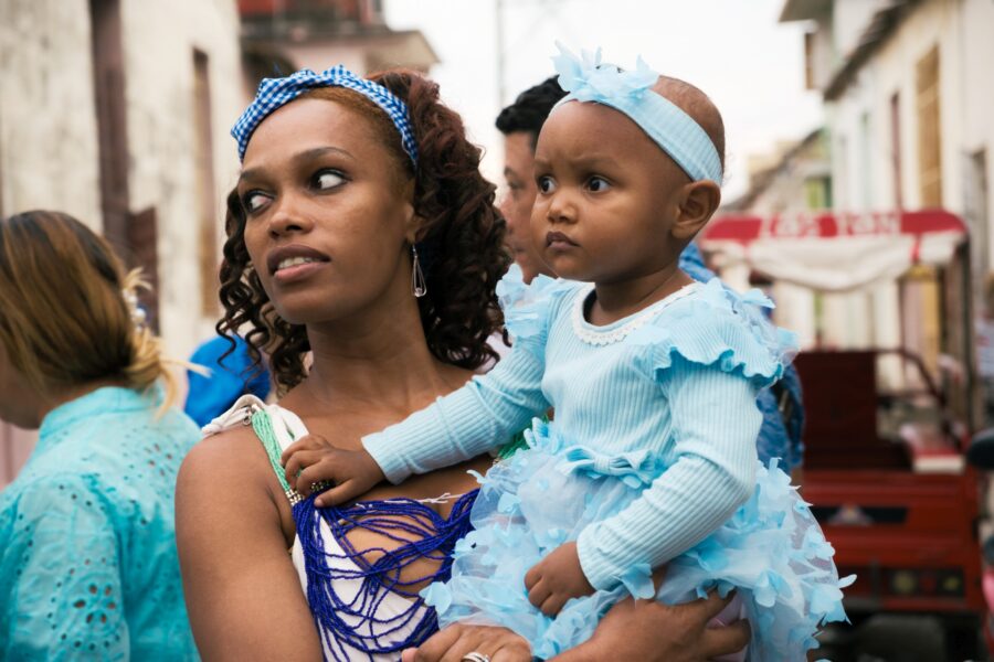 Madre lleva en brazos a su hija, ambas vistiendo los colores de la Virgen de Regla, también Yemayá en Regla de Ocha. Foto: Neus Pechero.