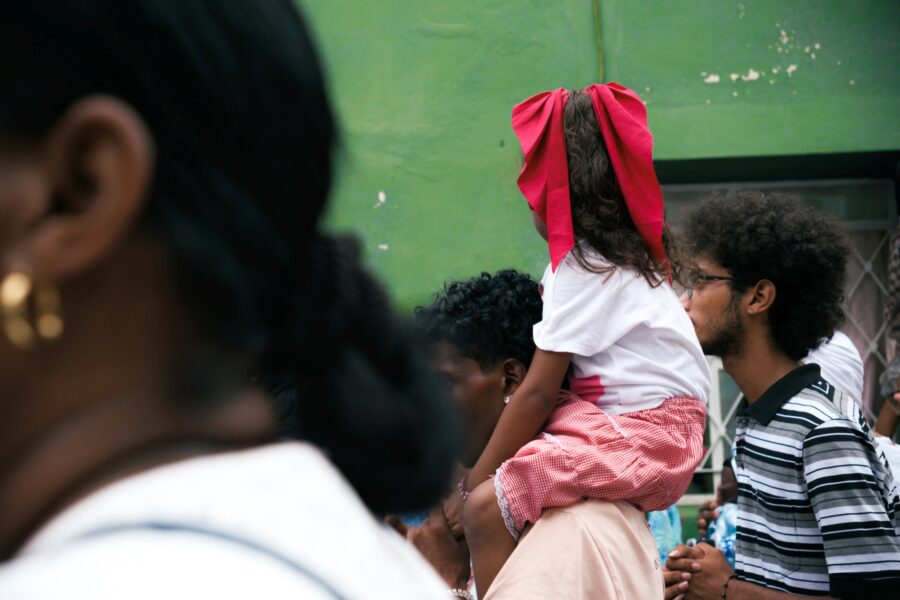 Niña llevada en los hombros por su padre mientras participan de la procesión de la Virgen de Regla. Foto: Neus Pechero.