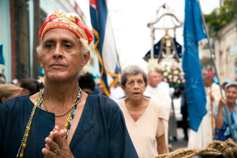 Practicante de Regla de Ocha camina delante de la Virgen de Regla y reza durante la procesión. Foto: Neus Pechero.